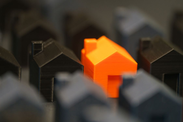 An orange-colored house placed amongst several black homes.